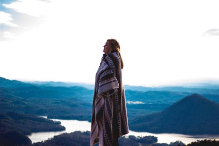 woman wearing coat standing on cliff photo