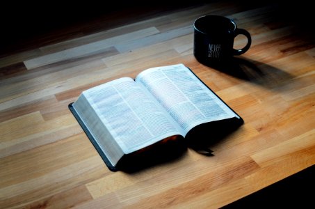 opened book beside black ceramic mug photo