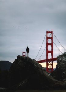 silhouette of man standing on rock near Golden Gate bridge photo