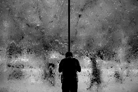 man standing on glass wall with pouring water photo