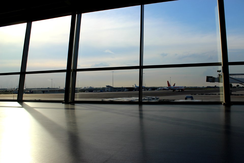glass panel window showing airplanes and runway under blue sky during daytime