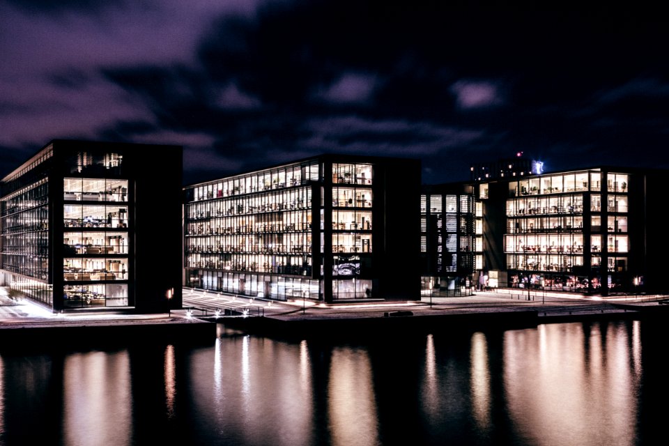 three concrete buildings near body of water during nighttime