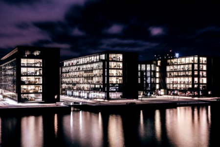 three concrete buildings near body of water during nighttime photo