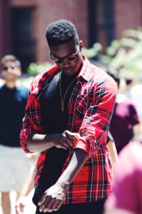 man fixing his red, black, and white plaid sport shirt sleeve during daytime photo