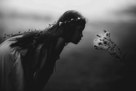 grayscale photo of girl looking at flowers photo