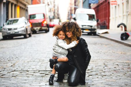 photography of woman carrying baby near street during daytime photo