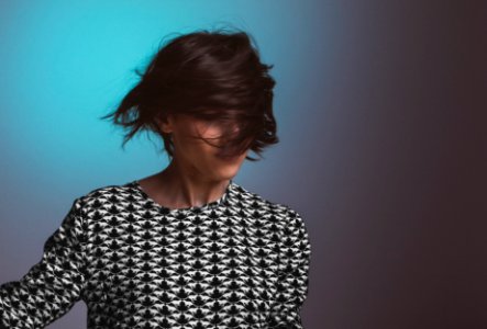Woman wearing a patterned sweater flips her short hair in front of her face photo