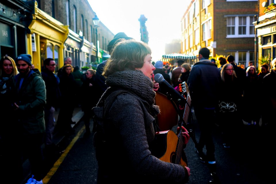 woman holding acoustic guitar while singing
