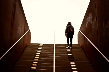 man in black jacket walking on brown wooden staircase
