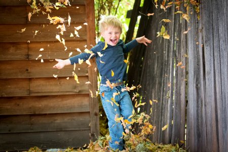 photo of boy near fence with falling leaves photo