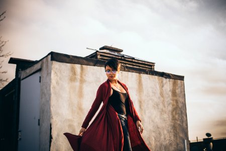 woman wearing red coat standing in front of white concrete structure photo