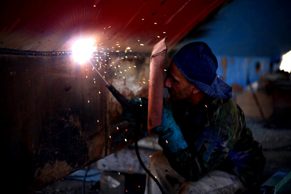 man welding the brown metal board