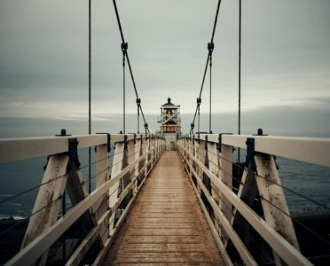 brown wooden lighthouse with bridge near seashore during daytime photo