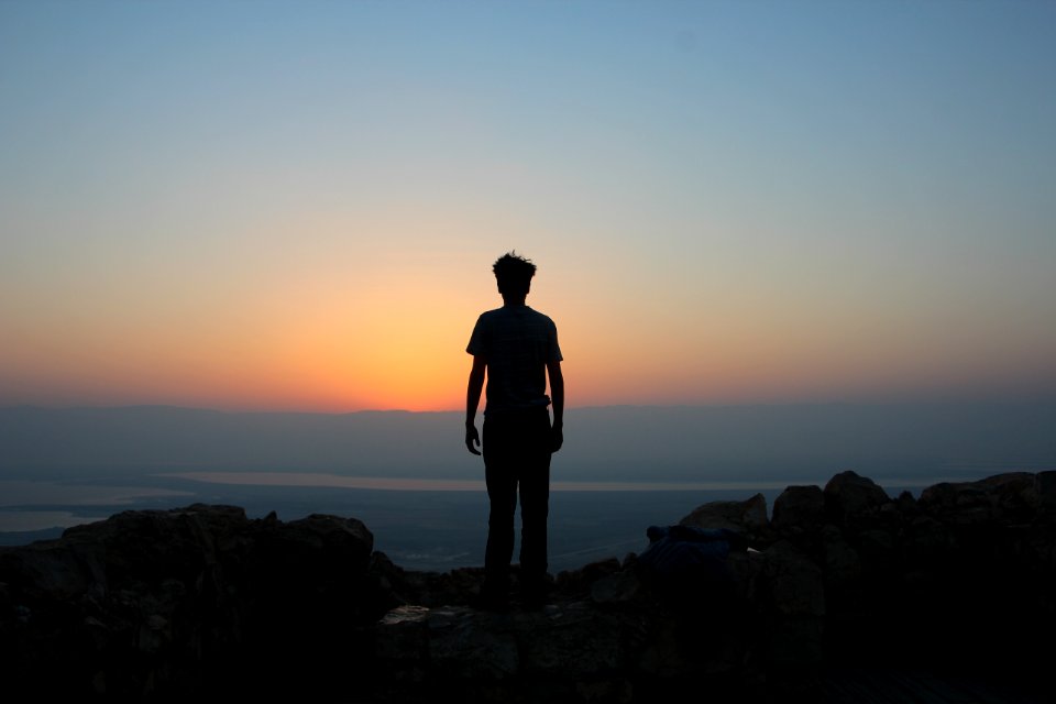 man standing on white stones looking in sea photo