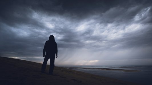 silhouette photography of person under gray clouds photo