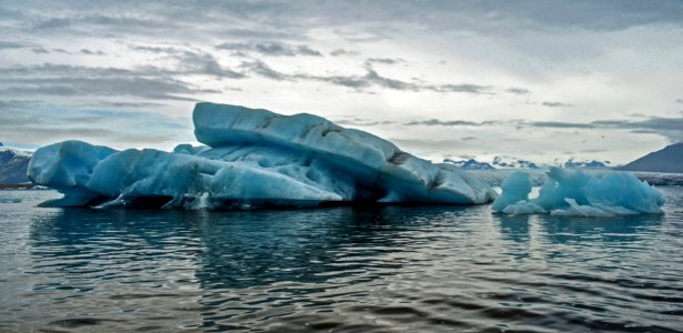 body of water with iceberg under cloudy sky photo