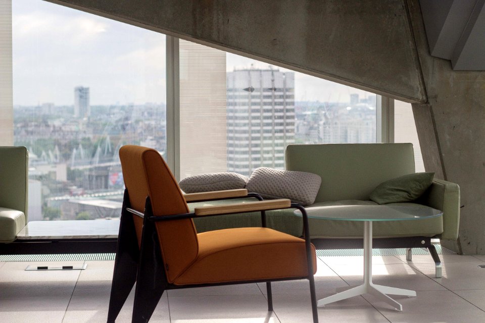 orange fabric padded armchair with black metal base near round clear glass-top table and gray sofa