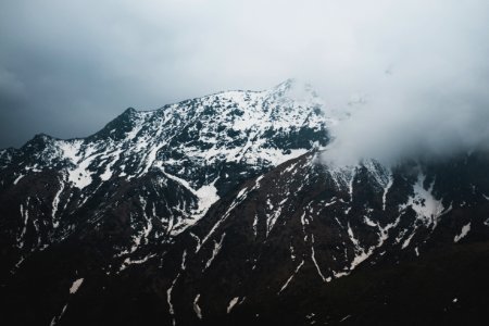 mountain covered with snow and surrounded with clouds photo