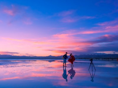 couple standing seashore while taking photo during golden hour photo