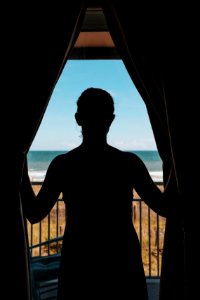 silhouette photo of woman standing between curtains photo