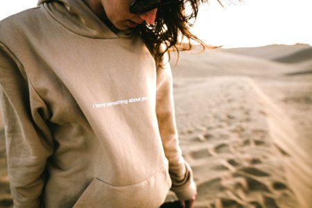 person wearing sunglasses and hoodie on sand photo