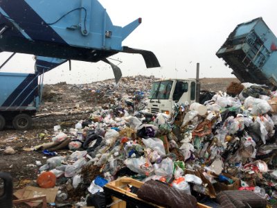 Bags of garbage getting emptied from trucks at a dump. photo
