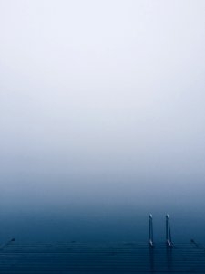 Lake pier with a ladder on serene waters on a foggy day