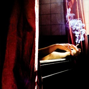 person holding cigarette near window photo
