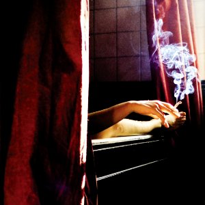person holding cigarette near window