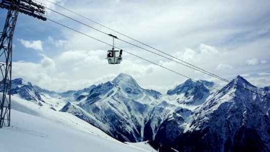 white cable car passing under snowfield during daytime