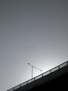 grayscale photo of bridge with postl ight