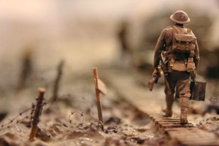 soldier walking on wooden pathway surrounded with barbwire selective focus photography photo