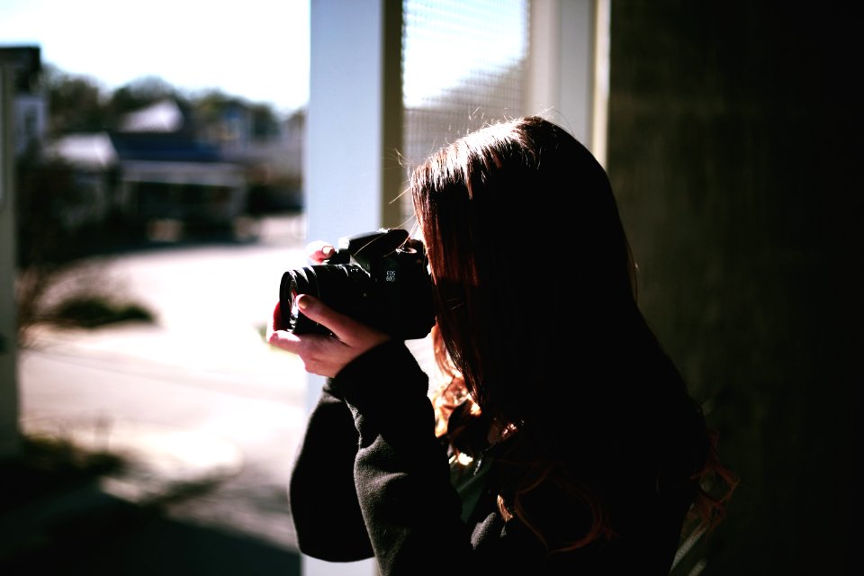 woman holding black DSLR camera