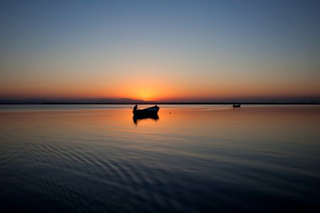 silhouette of boat on body of water during golden hour photo