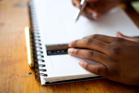 person holding ruler and pencil on spiral notebook photo