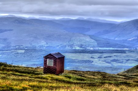 brown wooden house on green grass field near body of water during daytime photo