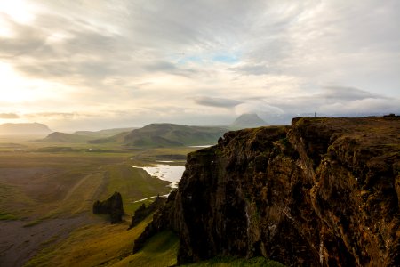 rocky cliff facing green grass fields photo