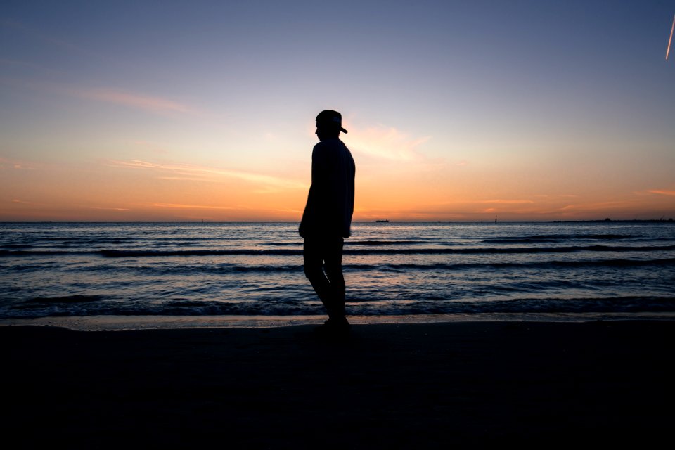 man standing on beach shore during daytime photo