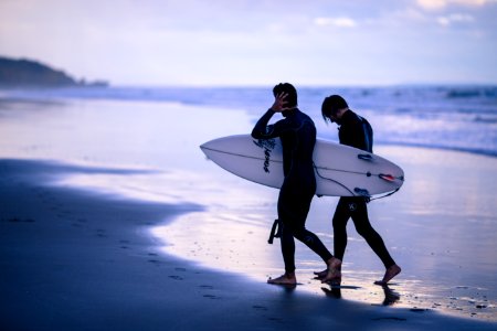 person walking on seashore holding surfboard photo