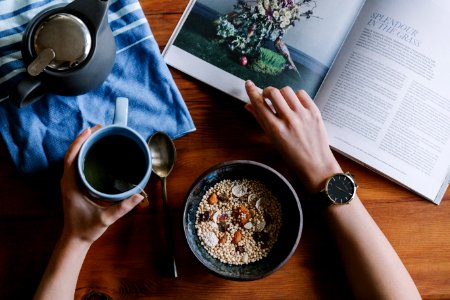 person holding blue ceramic mug and white magazine photo