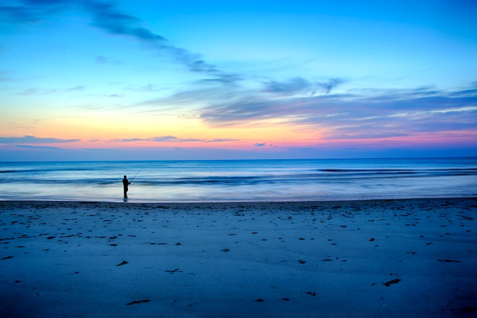 silhouette of person fishing on shallow part of sea
