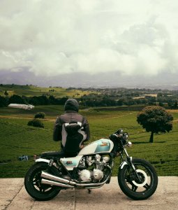 man sitting on motorcycle while facing broad green field photo