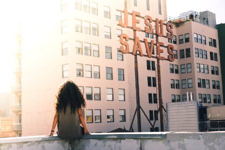 woman in gray top sitting on a building's edge photo