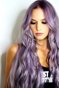 purple haired woman in black top leaning on wall photo