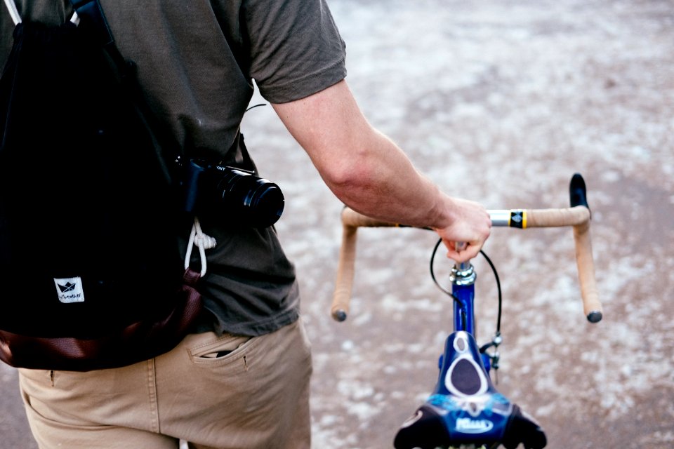 man holding brown and blue bicycle while walking outdoor during daytime