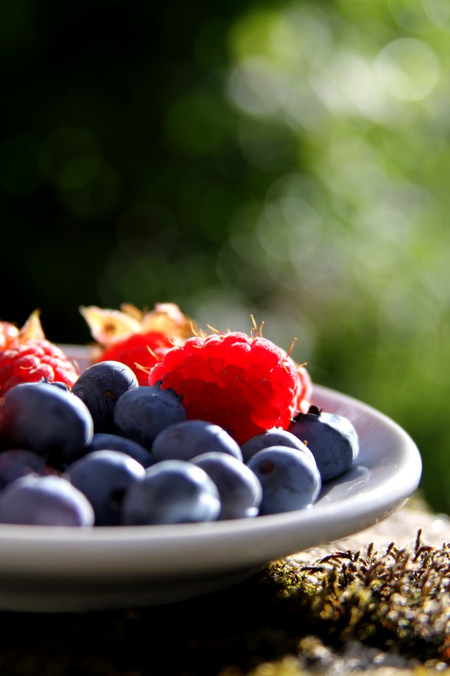 selective focus of blueberries and raspberries on bowl