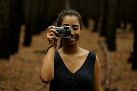 woman holding silver DSLR camera during daytime photo