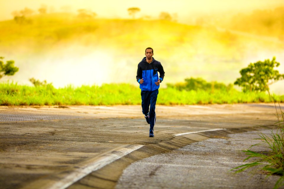 man in track suit jogging on concrete road