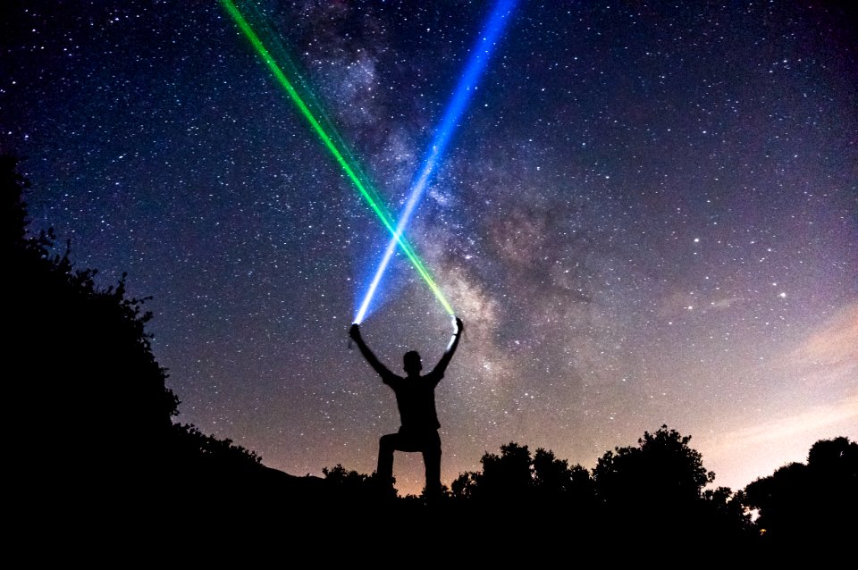 man holding green and blue flashlights