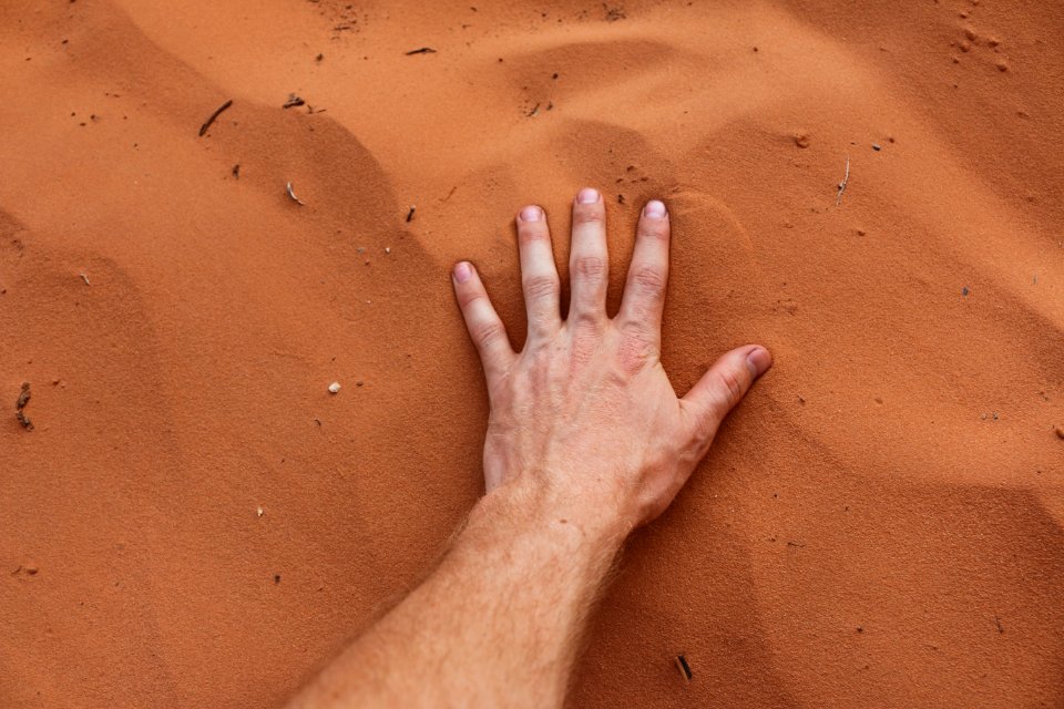 A person placing their hand on sand. photo